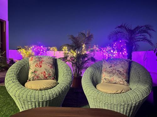 twee rieten stoelen in een kamer met paarse verlichting bij Flora A rooftop with serenity and peace in Jaipur