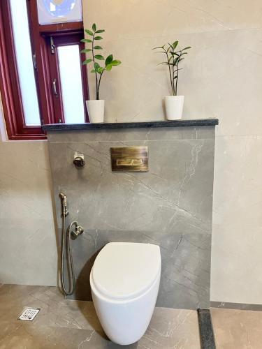 een badkamer met een toilet en 2 potplanten bij Flora A rooftop with serenity and peace in Jaipur