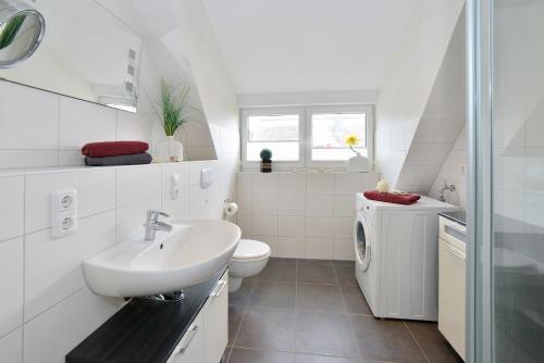 ein weißes Bad mit einem Waschbecken und einem WC in der Unterkunft Ferienhaus Boddenblick in Breege