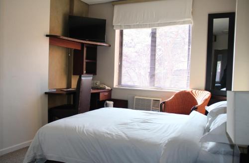 a bedroom with a bed and a desk and a window at Illovo Hotel in Johannesburg