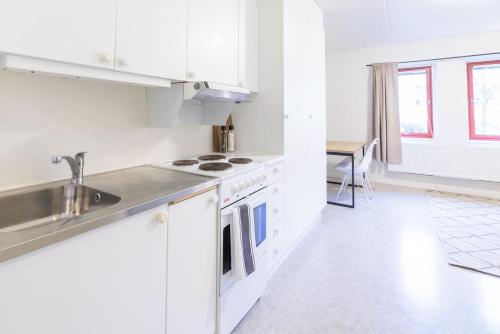 Una cocina con gabinetes blancos y un fregadero y una mesa. en Easy Livin' Apartment Hotel, en Växjö