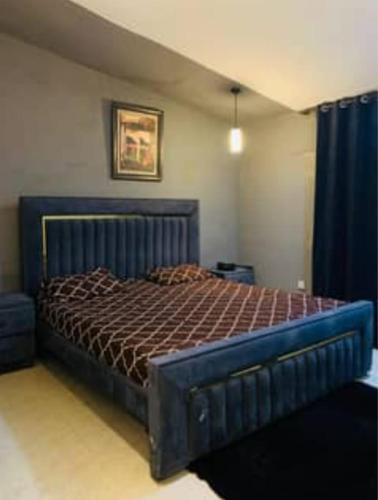 ein Schlafzimmer mit einem großen Bett mit blauem Rahmen in der Unterkunft Suites Inn in Faisalabad