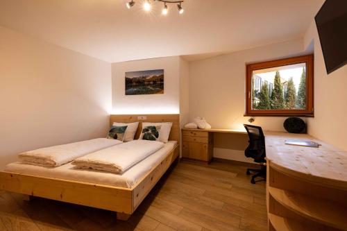een slaapkamer met een bed, een bureau en een raam bij Sirona Stay - Private Spa Retreat with garden, garage and Bolzano-Card in San Genesio Atesino