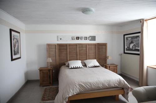 een slaapkamer met een bed met een houten hoofdeinde bij La Grange Ô Belles in Champfrémont