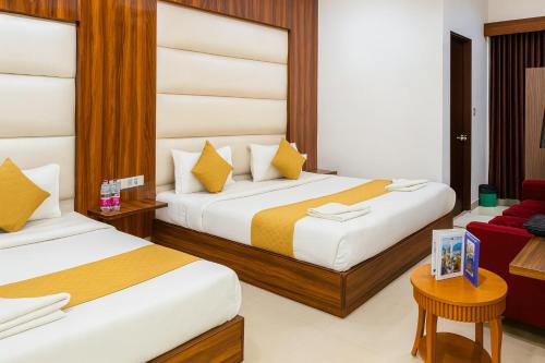 ein Hotelzimmer mit zwei Betten und einer roten Couch in der Unterkunft Hotel Earth By Aashiyana in Neu-Delhi