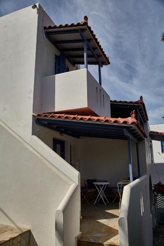 a white building with a dog sitting on a balcony at Irene Studios in ayios Petros