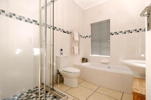 een witte badkamer met een toilet en een wastafel bij The Pelican in Langebaan