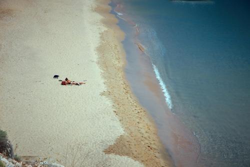 a group of people laying on a beach next to the water at Irene Studios in ayios Petros