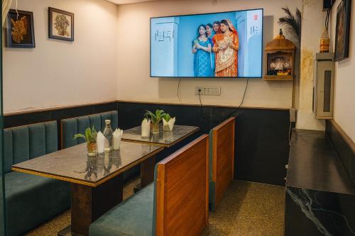 ein Esszimmer mit einem Tisch und einem TV an der Wand in der Unterkunft Hotel Earth By Aashiyana in Neu-Delhi
