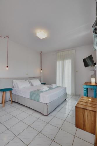 a white bedroom with a bed and a tv at Irene Studios in ayios Petros