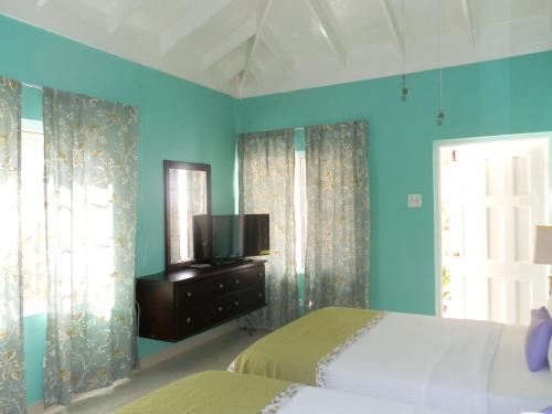 - une chambre avec des murs bleus, un lit et une télévision dans l'établissement Paradise on the Rocks, à Negril