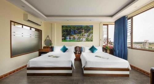 a bedroom with two beds and a large window at Viet Village Hotel in Noi Bai