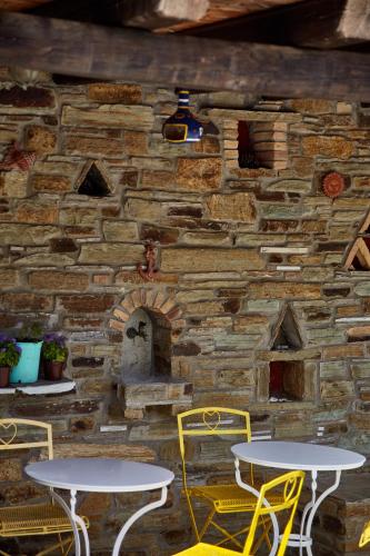 two tables and chairs in front of a stone wall at Irene Studios in ayios Petros