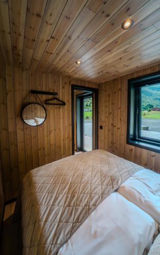 a large bed in a room with wooden walls at Flåm Minisuite in Aurland