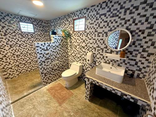 een badkamer met een toilet, een wastafel en een spiegel bij Lanna Maple House in Ban Thap Dua