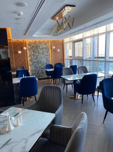 a dining room with tables and chairs and windows at AL HAYAT HOTEL in Sharjah