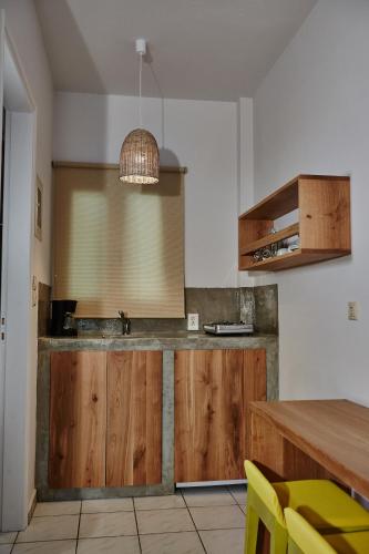 a kitchen with wooden cabinets and a table with yellow chairs at Irene Studios in ayios Petros