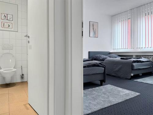 ein Schlafzimmer mit 2 Betten und ein Badezimmer mit einem WC in der Unterkunft Stuttgart Sky & Comfort Apartments in Stuttgart