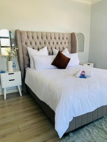 a large bed with white sheets and a large headboard at Khulanathi Guesthouse in Engcobo