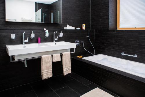 a bathroom with a white sink and a bath tub at Andermatt Alpine Apartments in Andermatt