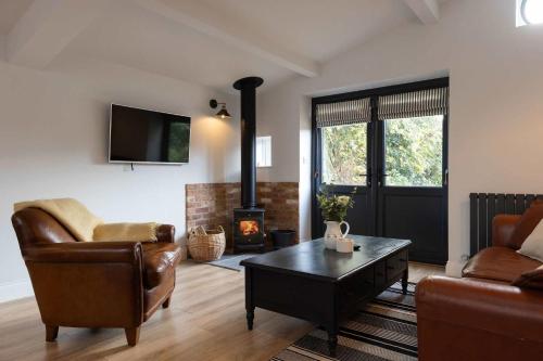a living room with a couch and a fireplace at Sidlesham Hideaway Logburner & Garden in Donnington