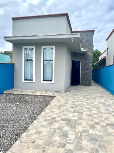 ein weißes Haus mit einer blauen Wand und einer Einfahrt in der Unterkunft Casa c ar condicionado à 600m mar in Itapoa