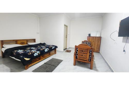 a bedroom with a bed and a chair at Kitty Royal Inn in Ooty