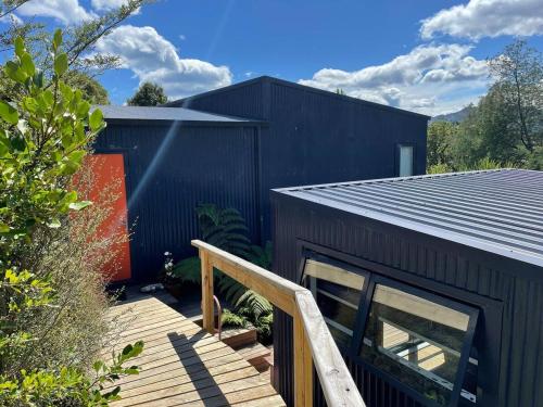 a black house with a wooden staircase next to a building at The Little Blue Haus - Pet Friendly Eco Pad, Nelson, NZ in Nelson
