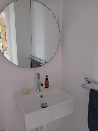 a white bathroom with a sink and a mirror at The Little Blue Haus - Pet Friendly Eco Pad, Nelson, NZ in Nelson
