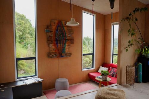 a living room with a red couch and windows at The Little Blue Haus - Pet Friendly Eco Pad, Nelson, NZ in Nelson