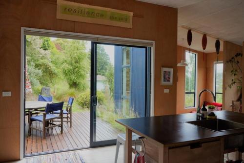 a kitchen with a sliding glass door leading to a deck at The Little Blue Haus - Pet Friendly Eco Pad, Nelson, NZ in Nelson
