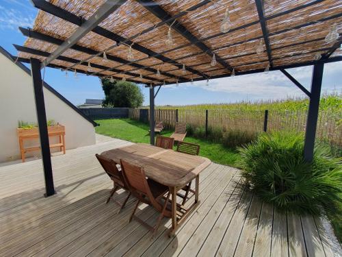 een houten tafel en stoelen onder een houten pergola bij La maison des Macareux - 5 min des plages in Lamballe Armor