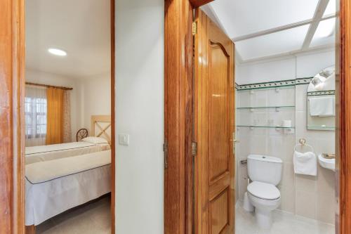 ein Bad mit einem WC, einem Waschbecken und einem Bett in der Unterkunft Playa Delphin 106 in Puerto Naos