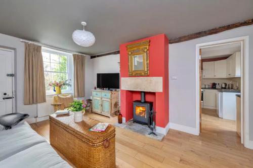 een woonkamer met een rode muur en een open haard bij Finest Retreats - Meadowsweet Cottage in Wingfield