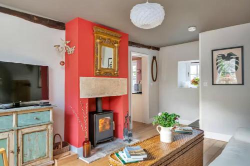 een woonkamer met een rode accentmuur en een open haard bij Finest Retreats - Meadowsweet Cottage in Wingfield