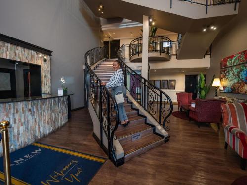 eine Person, die auf einer Wendeltreppe in einem Zimmer sitzt in der Unterkunft ANEW Hotel Highveld Emalahleni in Witbank