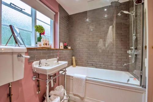 een badkamer met een bad, een wastafel en een douche bij Finest Retreats - Flittermouse Cottage in Wingfield