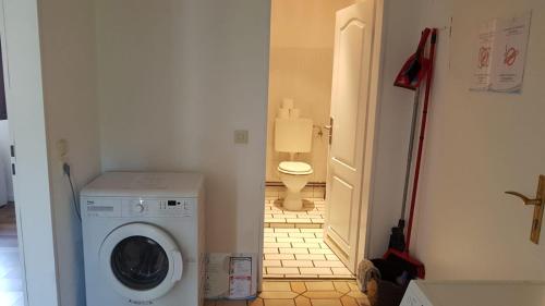 een wasmachine in een badkamer met toilet bij Süder11 - ApartB in Eddelak