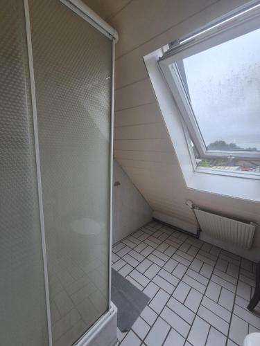 een badkamer met een douche en een raam bij Süder11 - ApartD in Eddelak