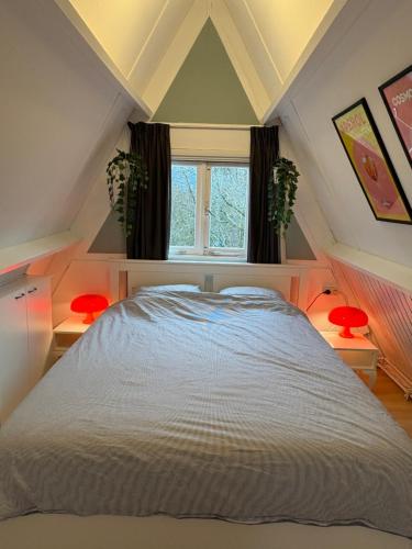 a attic bedroom with a bed and two windows at Heerlijk vakantiehuis in bos bij Durbuy in Durbuy