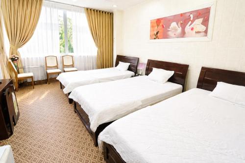 a hotel room with three beds and a tv at Lucky 1 Hotel in Trà Vinh