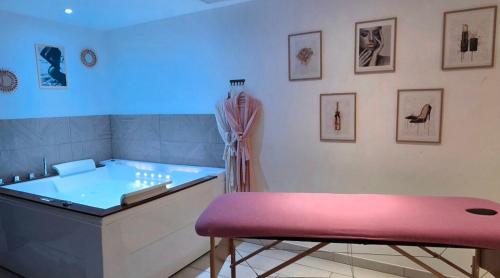 a bathroom with a tub and a pink stool at L'OLYMPE DES SENS in Portiragnes