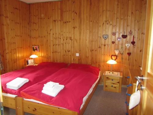 ツェルマットにあるZermatt Panoramic View Flatのベッドルーム1室(赤いベッド1台、タオル2枚付)