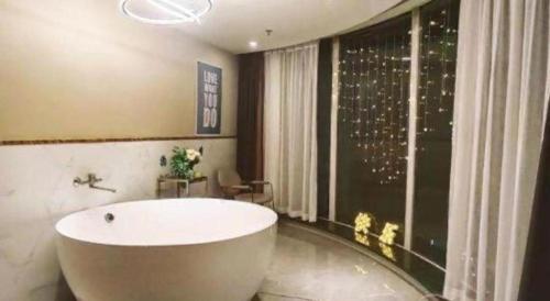 a bathroom with a large white tub and a window at Magnotel Shenyang Consulate Qingnian Street in Shenyang