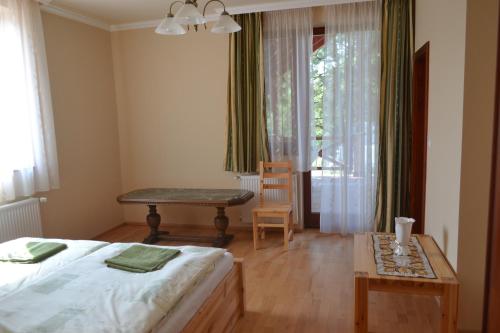 a bedroom with a bed and a table and a window at Módos Falusi Szálláshely in Bihartorda