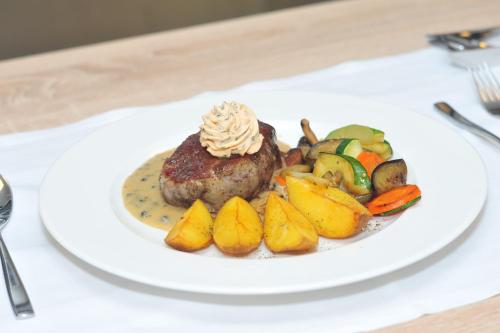 a plate of food with a piece of meat and vegetables at Thermal Hotel Balance Lenti in Lenti