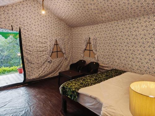 een slaapkamer met een bed, een stoel en een raam bij the jungle book - luxury camps by lake & woods in Bhīm Tāl