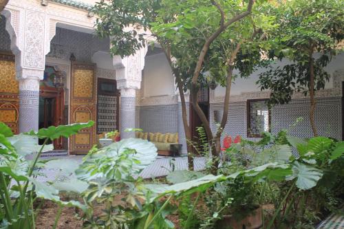 a garden with plants and trees in front of a building at Riad Les Chrifis Navette Aéroport 24 sur 24 in Fès