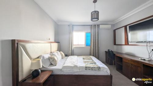 ein Schlafzimmer mit Bett, Schreibtisch und Fernseher in der Unterkunft Chic studio with parking and pool in Douala