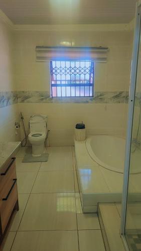a bathroom with a tub and a toilet and a window at kiddy in Mogwase